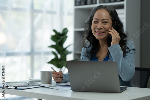Retirement businesswoman or senior executive using mobile phone to contact Negotiate financial business with partners. meeting to plan Analyze economic plans, taxes, office investments.