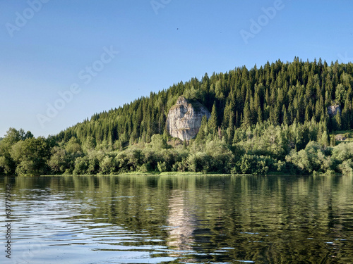 Landscape with the image of a mountain lake in the forest. The picturesque cliffs on the river bank