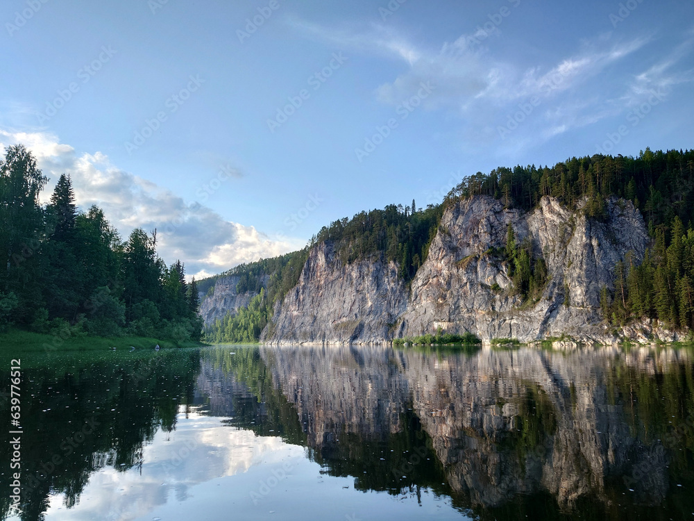Landscape with the image of a mountain lake in the forest. The picturesque cliffs on the river bank