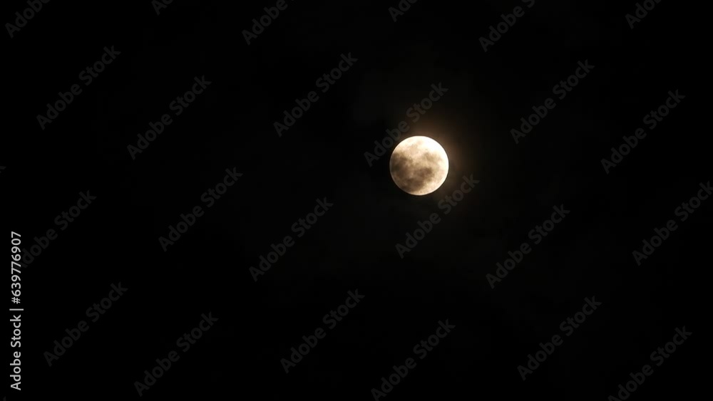 Clouds passing , in front of spooky illuminated moon surface Clouds passing , in front of spooky illuminated moon surface