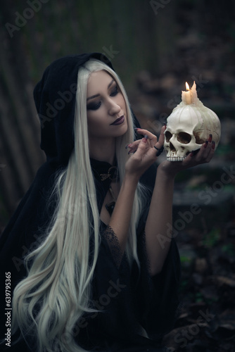 a blonde witch with long hair in a black hoodie on street on steps in mossy stones close-up
