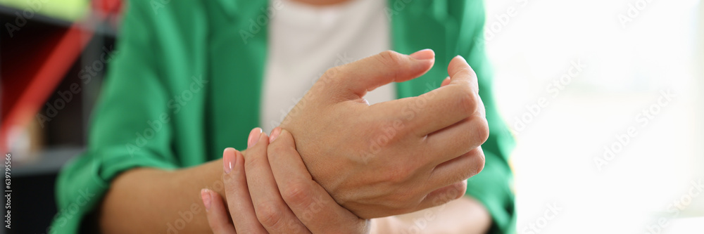 Close-up of female manager holding her painful wrist caused by long office work.
