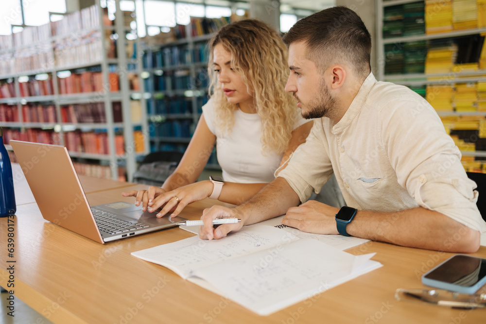 Boy help his girlfriend preparing for exam in public library. Education concept Boy help his girlfriend preparing for exam in public library. Education concept