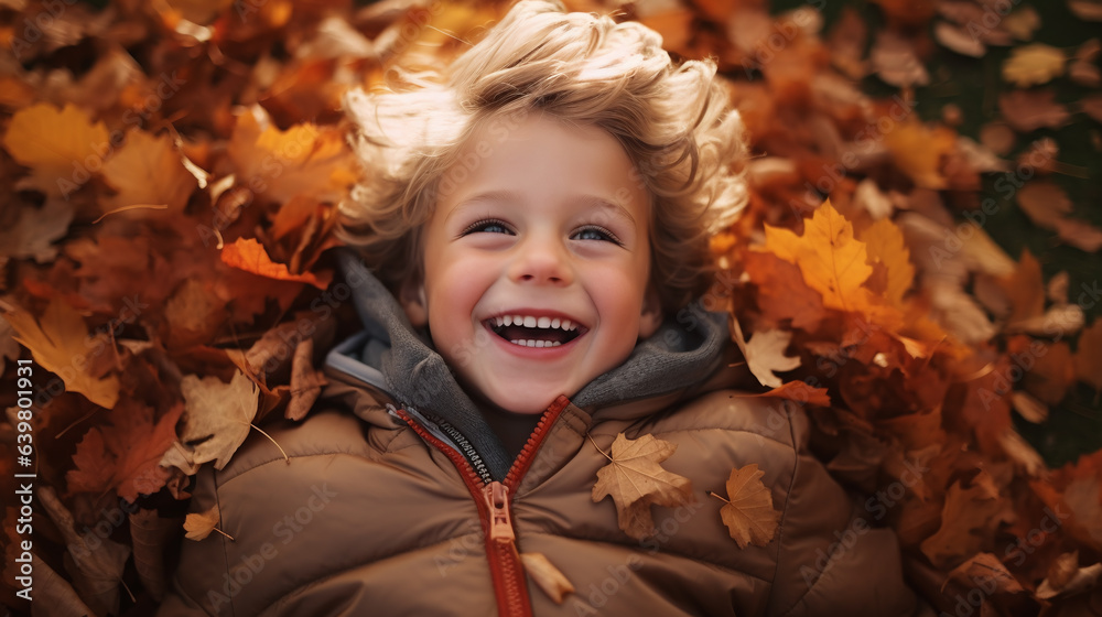 Cute and happy little boy laying on fallen leaves. Having fun outdoor during autumn season. Cute and happy little boy laying on fallen leaves. Having fun outdoor during autumn season.
