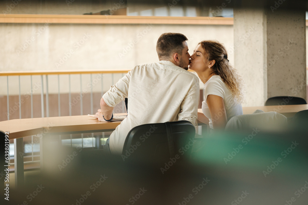 Back view of boy and girl have fun in library during the study. Preparing for examines in university. Education concept Back view of boy and girl have fun in library during the study. Preparing for examines in university. Education concept