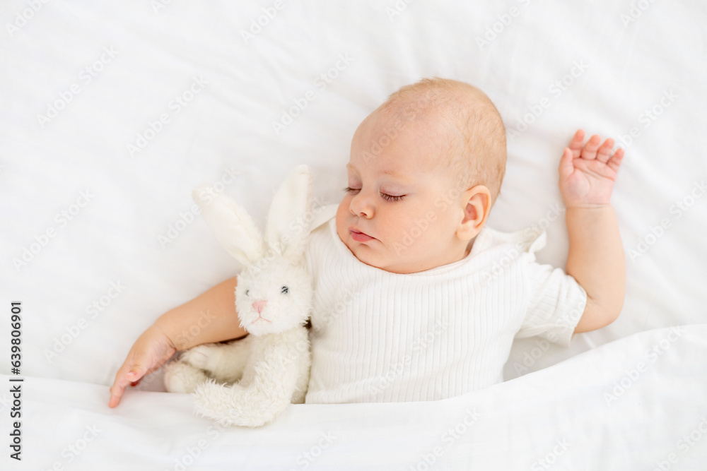 cute little newborn baby sleeping under a blanket hugging a plush bunny, sweet healthy baby sleep in a white crib, a place for text