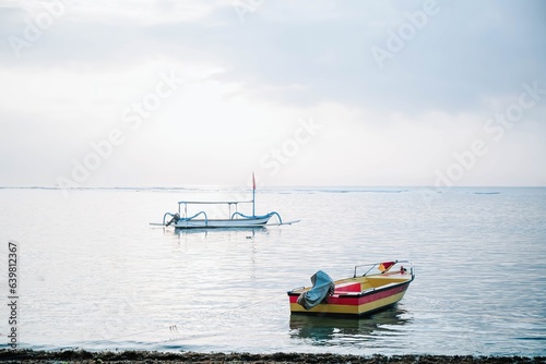 Portrait or vertical shot of a colorful boat with traditional boat floating on the beach in the morning. Selective focus.