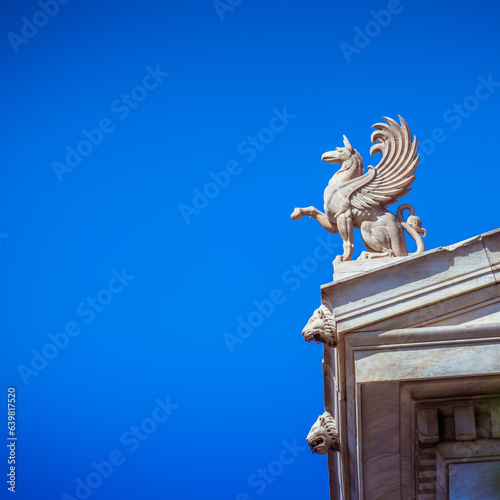 A Griffon, statuette stands on the roof of Athens National University. Since antiquity, griffins were known for guarding treasures and priceless possessions. Cultural travel in Greece. photo