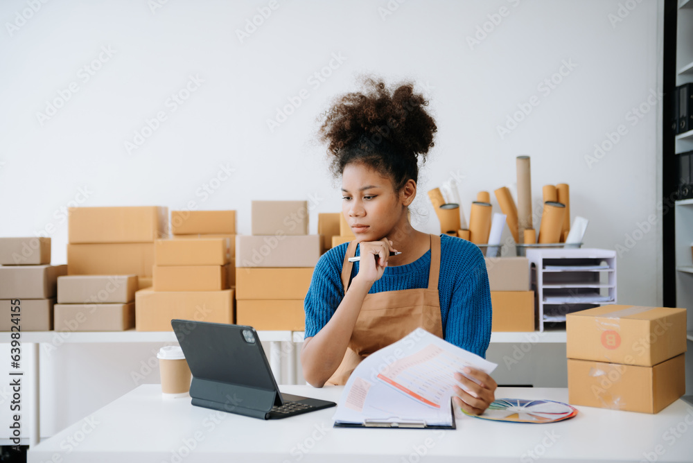 Young woman holding a smartphone, tablet showing payment success and credit card with yellow parcel box as online shopping concept Young woman holding a smartphone, tablet showing payment success and credit card with yellow parcel box as online shopping concept