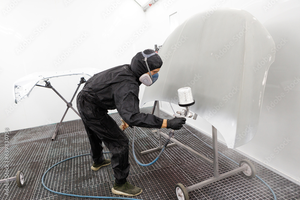 Automotive paint services : Male painters who are skilled in using automotive paint sprayers wearing masks to prevent spray paint dispersion work in a closed spray booth for health and quality work - obrazy, fototapety, plakaty 
