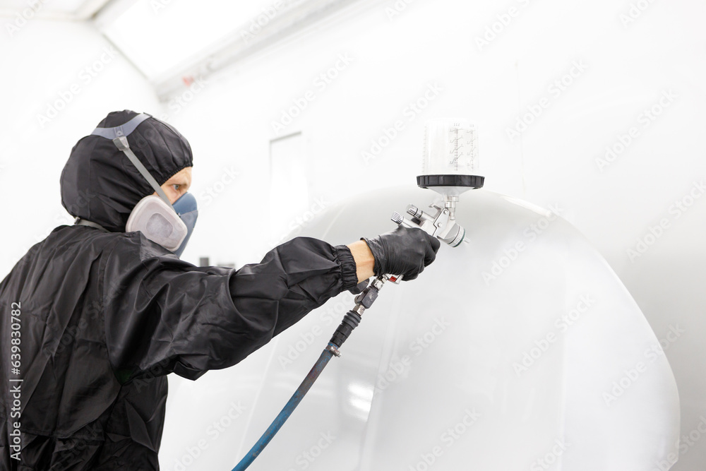 Automotive paint services : Male painters who are skilled in using automotive paint sprayers wearing masks to prevent spray paint dispersion work in a closed spray booth for health and quality work
