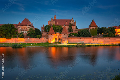 The Castle of the Teutonic Order in Malbork by the Nogat river at dusk. Poland