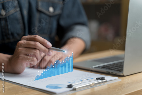 Analysis business growth trends and the company finances. Businessman working touching on laptop with virtual image bar, pen pointing to blue chart on document. Future results, performance reports