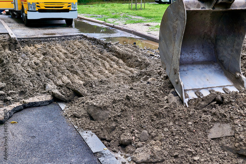 Excavator bucket picking up the ground, soil on road repair