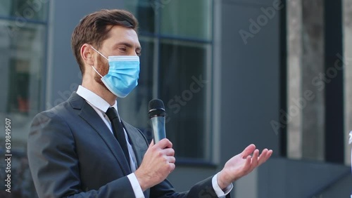 Multiracial representative doctor giving interview to the male journalist correspondent wearing protective mask. Reporting live near building. Pandemic concept. COVID-19. Medicine and healthcare. photo