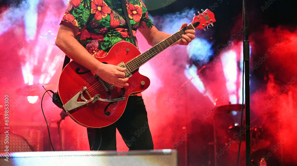 Obraz premium A guitarist plays an electric guitar on stage during a concert. Musician with guitar at festival.