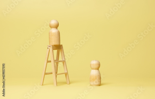 A picture of men wooden peg doll on top of ladder and women peg doll below. Job opportunity, discrimination, gap and climbing hierarchy concept.
