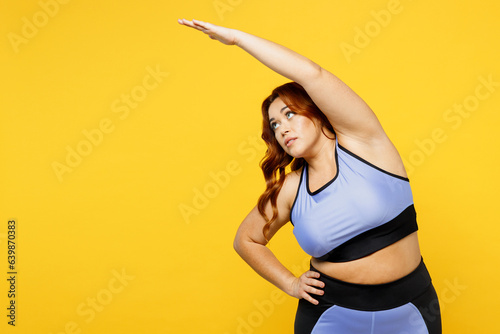 Young overweight plus size fat fit woman wear blue top warm up training tilt body to sides with hand, stretch lunge exercise isolated on plain yellow background studio home gym. Workout sport concept.