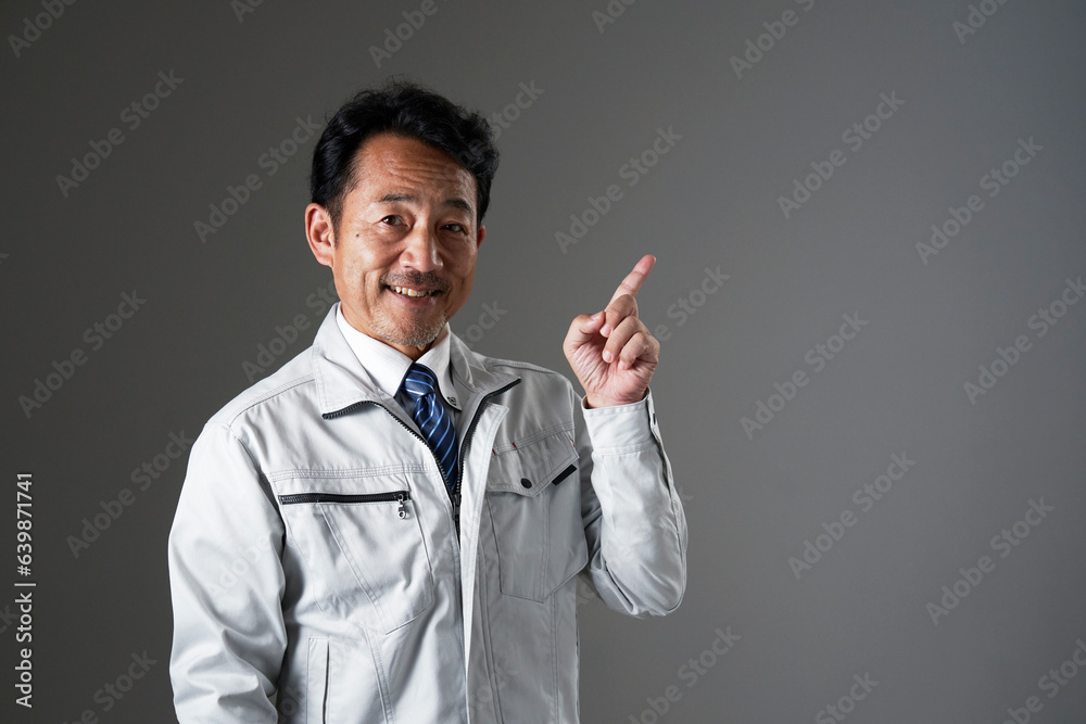 右側を指差すミドルエイジの作業員　黒背景