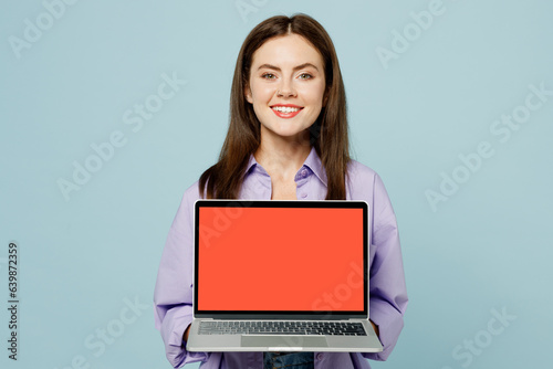 Young IT woman wears purple shirt yellow t-shirt casual clothes hold use work on laptop pc computer with blank screen workspace area isolated on plain pastel light blue background. Lifestyle concept.