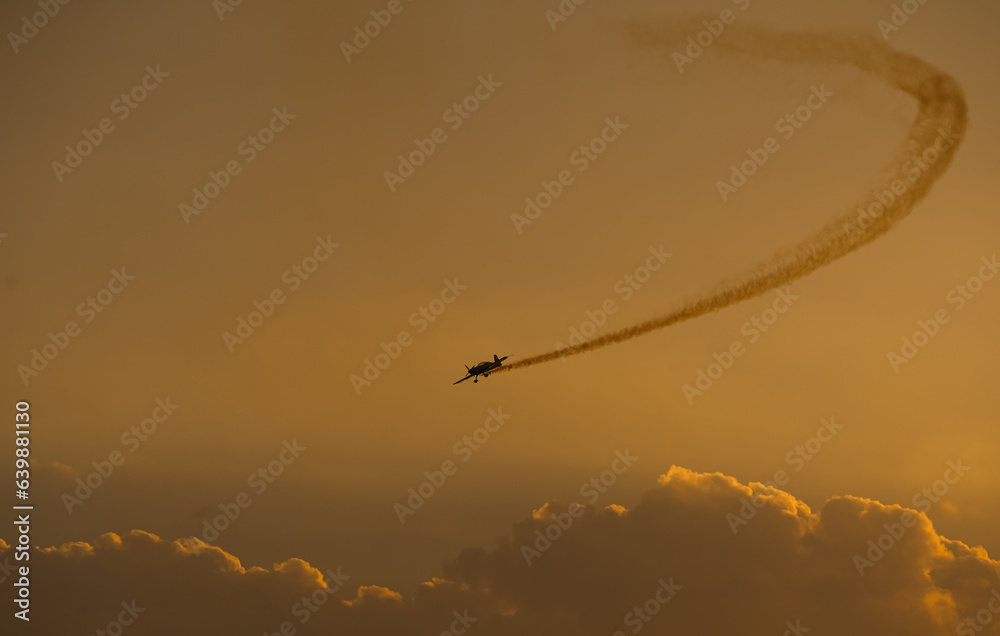 Obraz premium Aerial acrobatics airshow. Ultra light airplanes doing acrobatics in air against amazing sunset sky. Aviation industry concept image.