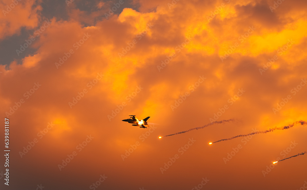 Fighter jet super sonic speed military air planes flying against sunset sky and shooting fire during a demonstrative air show. Military aviation concept image.