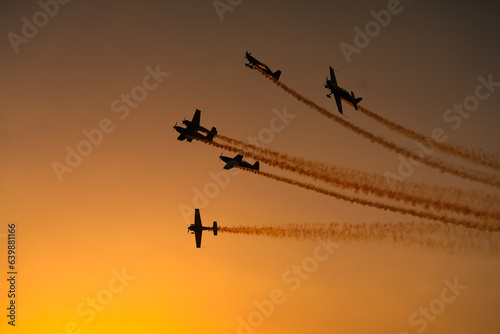 Aerial acrobatics airshow. Ultra light airplanes doing acrobatics in air against amazing sunset sky. Aviation industry concept image.