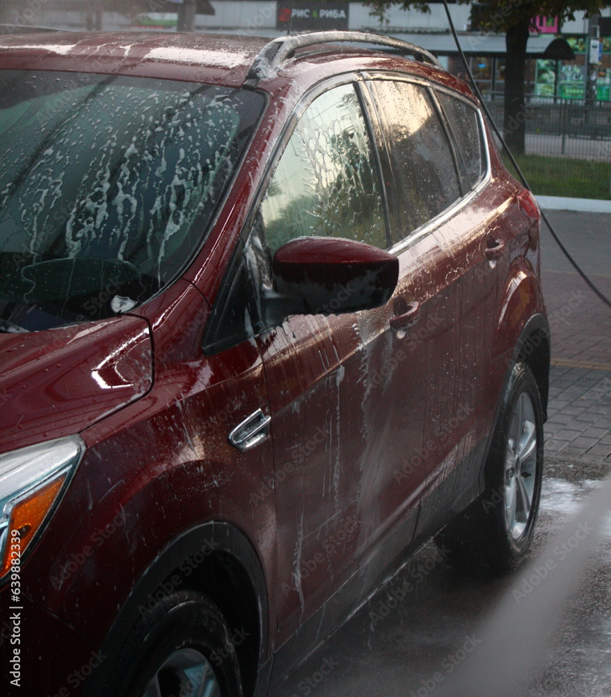 washing a car outside, a red car at a car wash, outdoor