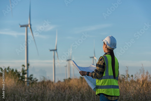 portrait of a person in wind turbine farm.  Woman engineers with drawing against turbines on wind turbine farm.