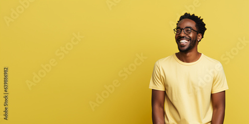 Attractive african american man wearing yellow tshirt and glasses. Isolated on yellow background. 