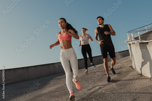 Foto Three confident young people in sportswear looking concentrated while running ou