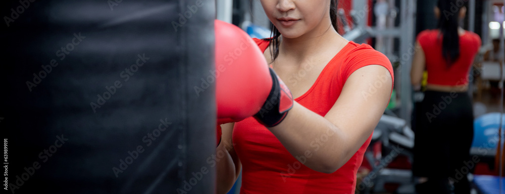Determination of young asian woman having motivation boxing in fitness gym, active sport and workout, training boxing with strength and confidence, health and wellness, exercise and punch with cardio.