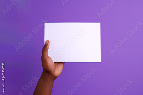 A human hand holding a blank sheet of white paper or card isolated on purple background
