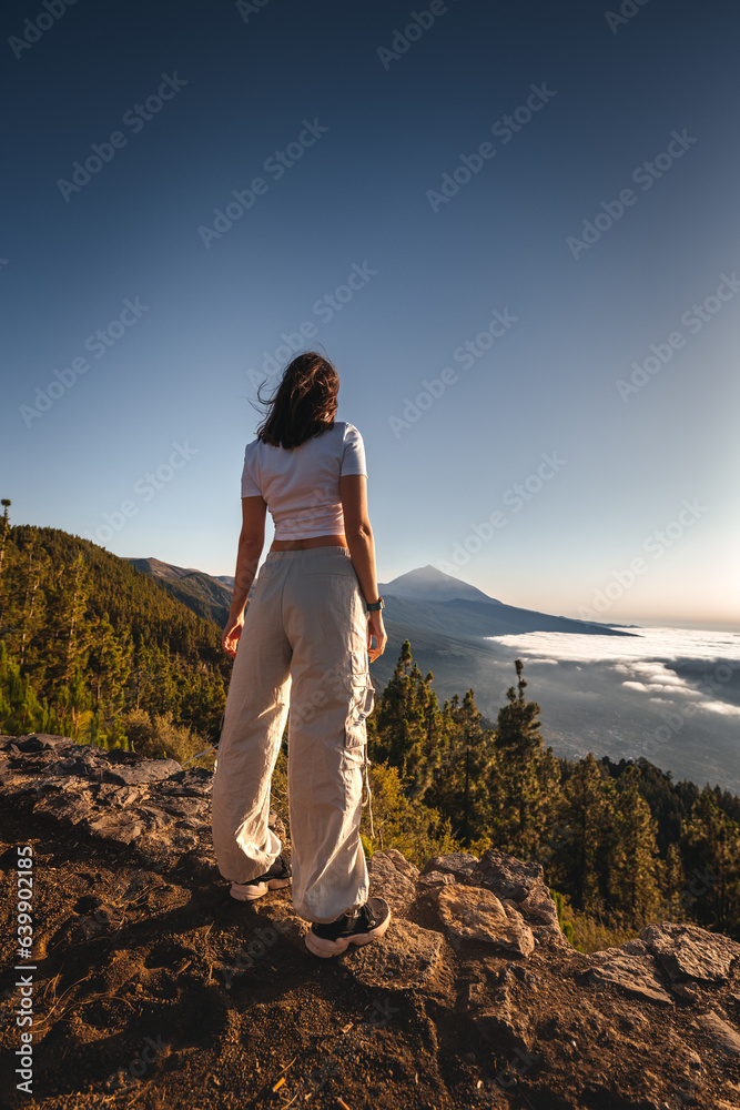 Girl standing on a rock above the clouds in front of volcano Teide, Tenerife