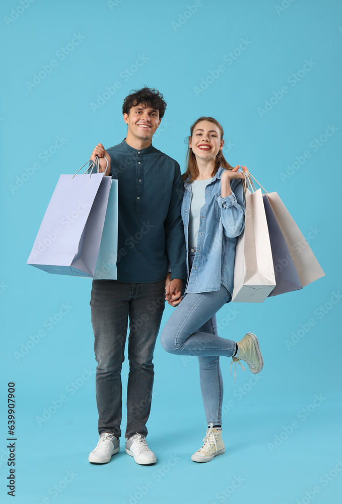 Happy young couple with shopping bags on blue background Happy young couple with shopping bags on blue background