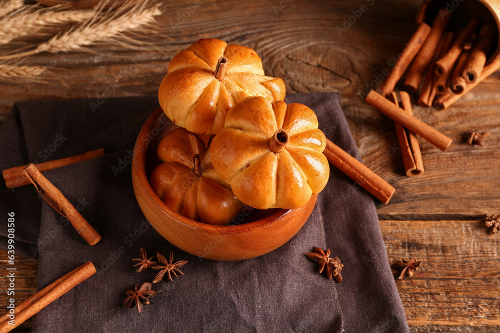 Bowl with tasty pumpkin shaped buns on wooden background Bowl with tasty pumpkin shaped buns on wooden background
