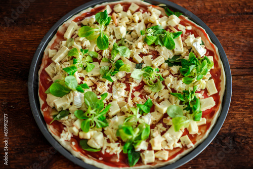 Pizza with lots of cheese and herbs. Cheesy pizza in a round shape on a wooden background. Top view.