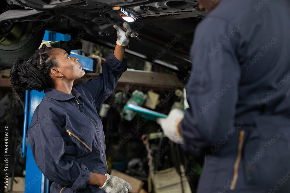 African female mechanic checking and fixing underneath car in automobile repair shop