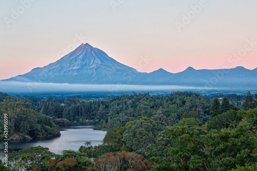 Peaceful scene at dawn over Lake Mangamahoe on New Zealand   s North Island  surrounded by lush rainforest with Mt Taranaki in the background