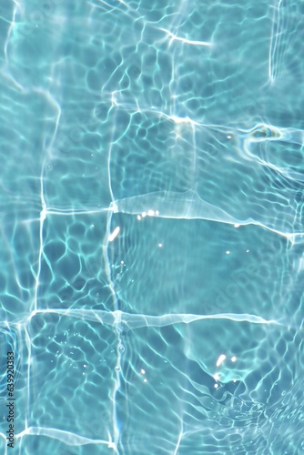 Blue water with ripples on the surface. Defocus blurred transparent blue colored clear calm water surface texture with splashes and bubbles. Water waves with shining pattern texture background.