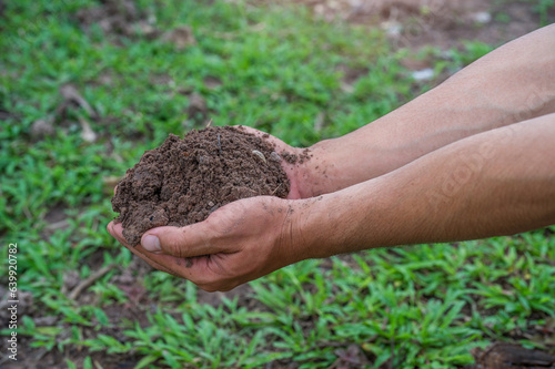 Hand holding fertile black soil. Hands holding good quality soil. Dirty hands with soil. Hand holding soil in agricultural field.