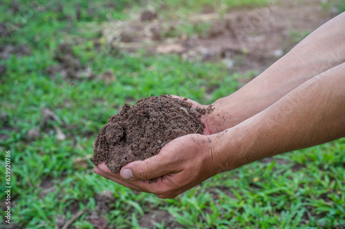 Hand holding fertile black soil. Hands holding good quality soil. Dirty hands with soil. Hand holding soil in agricultural field.