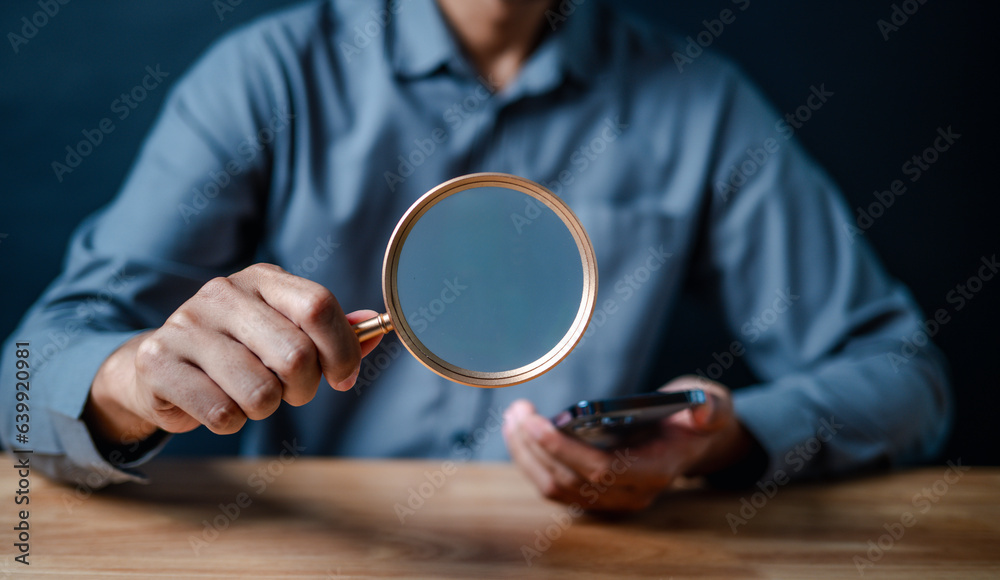 smartphone, magnifier, close up, hand, businessman, portrait, background, blue, play, formal. picture is close up to businessman, him hold smart phone and another hand hold magnifier for finding.
