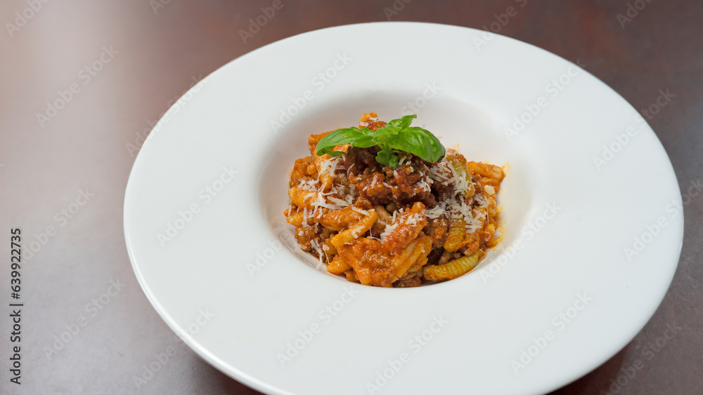 malloreddus or Sardinian gnocchetti, typical Sardinian pasta, with wild boar sauce, basil and pecorino cheese.