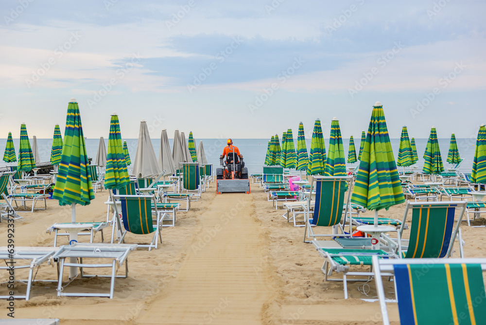 many closed umbrellas and sun loungers on an empty beach. Start or end of the season concept.