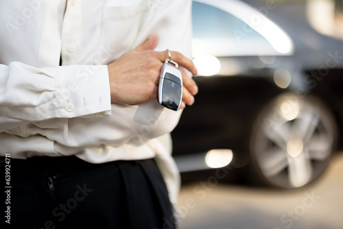 Business woman holds a keychain of a luxury car outdoors  close-up. Concept of business transfer service and transportation