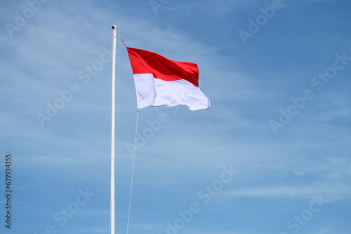 Indonesian flag with blue sky background, waving red and white flag