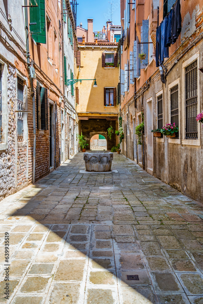 Narrow pedestrian cabblestone old alleys in Venice, Italy. Old worn out medieval buildings.