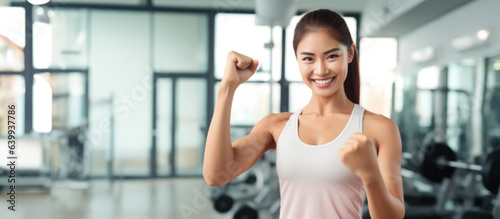 Asian female fitness trainer smiling at camera in fitness background