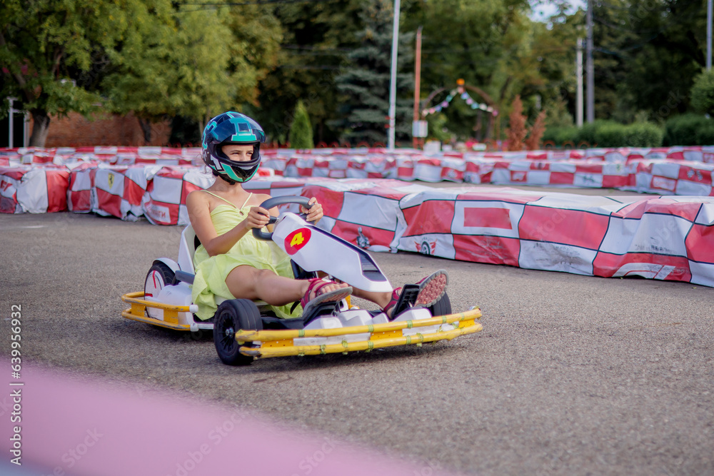 A young go-kart racer on the racetrack. The concept of speed and sports for children in the summer